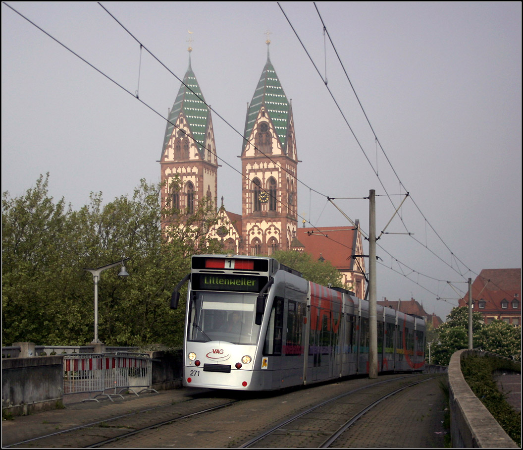 Über den Hauptbahnhof hinweg in den Freiburger Westen -

Eine Combino-Tram fährt die westliche Rampe zur Stühlinger Brücke hoch und wird gleich die Haltestelle Hauptbahnhof erreichen. Im Hintergrund die Herz-Jesu-Kirche im Stühlinger.

11.05.2006 (M)