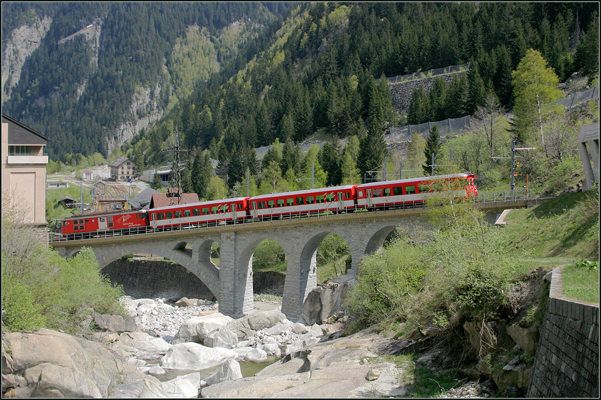 Über die schräge Brücke -

Der Regionalzug von Andermatt befindest er sich auf der schrägen Bogenbrücke über die Reuss kurz vor dem Bahnhof Göschenen.

12.05.2008 (M)