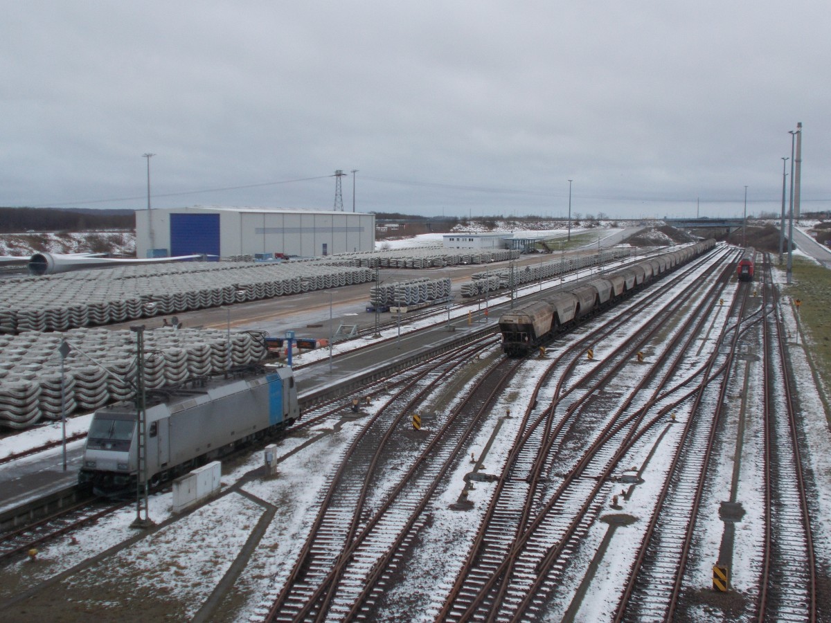 Überblick über den Bahnhof Mukran am 07.Februar 2015 hatte man von der Fussgängerbrücke aus,wo die Railpool 186 147 am Bahnsteig stand,eine Schlange Getreidewagen und die schon seit längerem abgestellten Dostos.