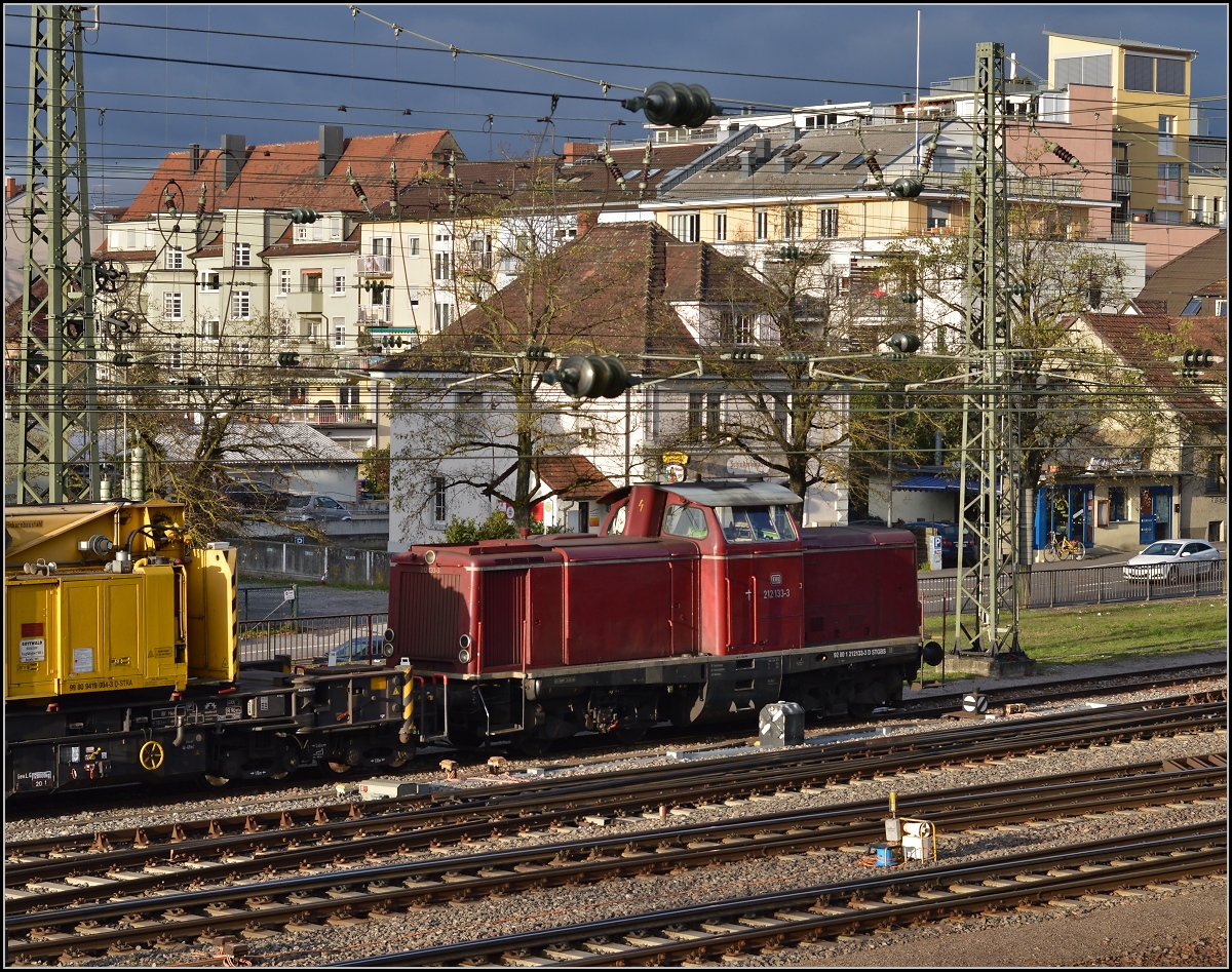 <U>Lichtspiele in Singen am Hohentwiel.</U> 

212 133-3 vor dunklem Himmel. Nach einem Rangierunfall mit einigen Güterwägen hatte die Lok die  Aufgleishilfe  nach Singen gebracht. November 2013.