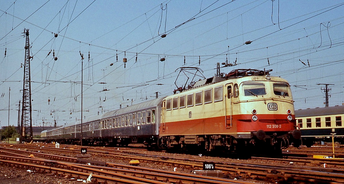 Um 1980 fährt die 112 308-2 mit einem Eilzug in den Dortmunder Hauptbahnhof ein. Die Lok wurde als E 10 1308 am 21.10.1963 für die Beförderung des  Rheinpfeil  beschafft. Nach der Indienststellung der 103 wanderte sie in untergeordnete Dienste ab und wurde am 23.11.2004 verschrottet.