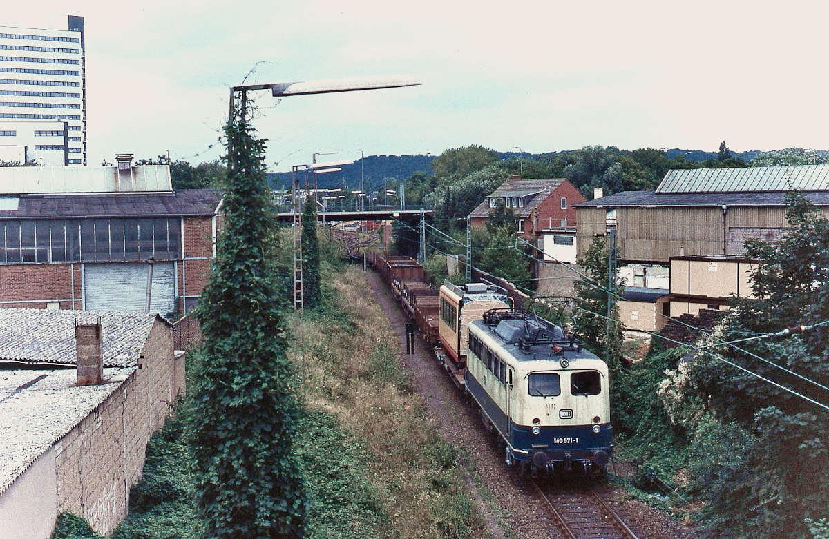 Um 1990 verlässt 140 571-1 den Güterbahnhof Düsseldorf-Grafenberg in Richtung Düsseldorf-Derendorf. Bis zur Schließung des Duewag-Werkes im Jahre 2000 wurden auch Triebwagen(-teile) über Grafenberg abtransportiert (s. auch das Triebwagen-Mittelteil auf dem Flachwagen direkt hinter der Lok). Wenige Jahre später wurde auch der Güterbahnhof stillgelegt.