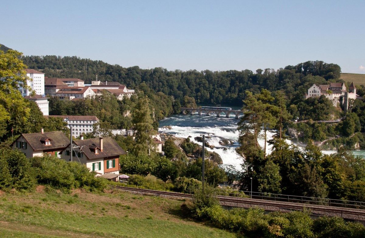 Um das Bahnbildertreffen noch internationaler zu machen reiste eine kleinere Gruppe Fotografen gegen den frühen Abend noch in die Schweiz nach Neuhausen am Rheinfall.
Auf der eigentlichen Rheinfallbahn überquert gerade ein Thurbo RABe 526 die Brücke. Im Vordergrund sichtbar sind die Gleise der direkten Strecke nach Zürich, während sich im Rücken der Fotografen die Badische Hauptbahn befindet.
Bahnbildetreffen in Singen - Neuhausen am 2. August 2015