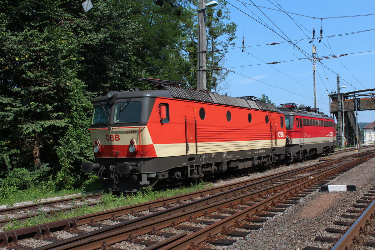 Um die Mittagszeit des 6.7.2019 sonnen sich die 1144 092 und die 1142 667 im Bahnhof Spielfeld-Straß beim Warten auf ihre nächste Leistung.