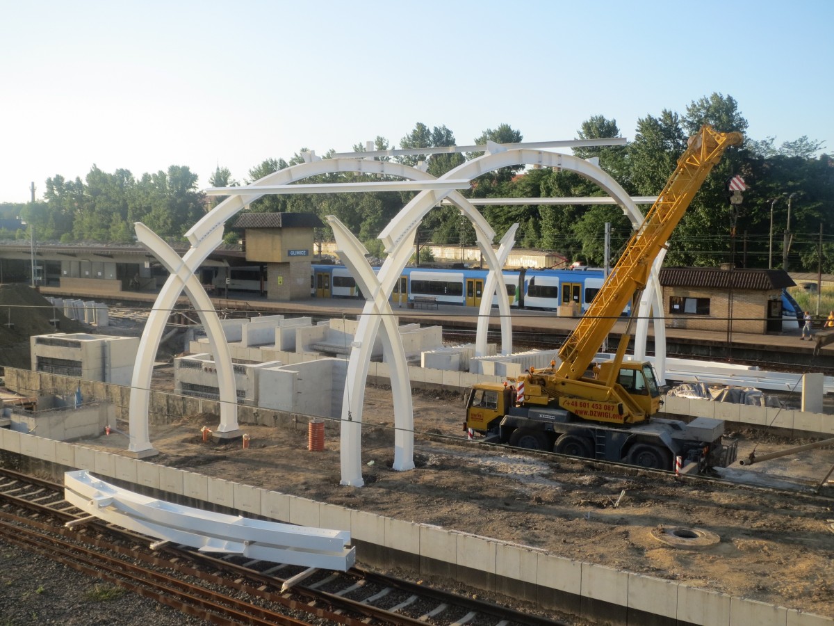 Umbau bzw. Renovierung vom Hauptbahnhof Gleiwitz (Gliwice) schreiten voran. Am 2. Juli 2015 wurde mit der Aufstellung der Säulen für die neue Bahnhofshalle begonnen, von denen am Abend zwei Elemente standen. Foto von der provisorischen Bahnüberführung zwischen den Bahnsteigen.