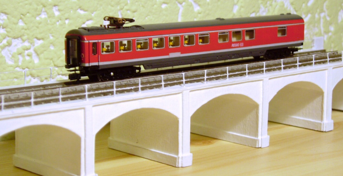 Umlackierter Wrmz von Fleischmann. Die Beschriftung stammt von Herrn Nothaft, derzeit fehlen noch die Langträgerbeschriftung, Bistro- und Südostbayernbahnschriftzug. Der Tieferlegung erster Schritt erfolgte bereits mit 5,2mm Tomschke-Radsätzen, wenn die neuen KKK-Deichseln eintreffen wird die Höhe noch an die Halberstädter von Arnold angepasst.
Zustand vom 04.05.2015, der Wagen steht auf einem Stadtbahnviadukt, Peco55 (gefertigt aus Pappe, Messingstiften und weißem Zwirn) im Stil eines Architekturmodells, was künftig Teil einer Modulmodellbahn werden soll.