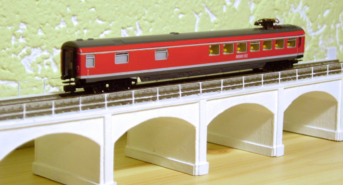 Umlackierter Wrmz von Fleischmann. Die Beschriftung stammt von Herrn Nothaft, derzeit fehlen noch die Langträgerbeschriftung, Bistro- und Südostbayernbahnschriftzug. Der Tieferlegung erster Schritt erfolgte bereits mit 5,2mm Tomschke-Radsätzen, wenn die neuen KKK-Deichseln eintreffen wird die Höhe noch an die Halberstädter von Arnold angepasst.
Zustand vom 04.05.2015, der Wagen steht auf einem Stadtbahnviadukt, Peco55 (gefertigt aus Pappe, Messingstiften und weißem Zwirn) im Stil eines Architekturmodells, was künftig Teil einer Modulmodellbahn werden soll.