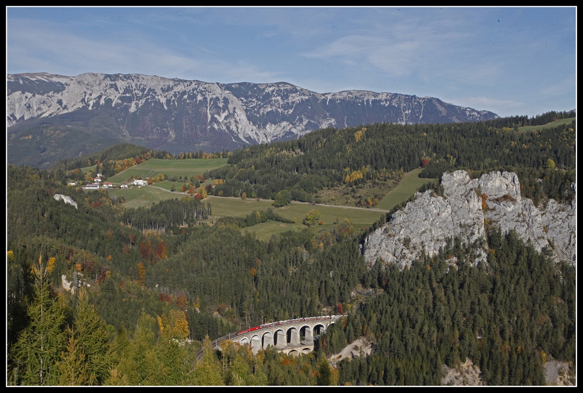 Umrahmt von der Semmmeringer Bergwelt ziehen eine 1144 und ein Taurus einen Güterzug am 17.10.2019 über den Kalte - Rinne - Viadukt.