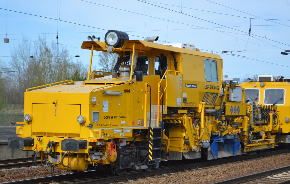 Universalschotterverteil- und Planiermaschine für Gleise und Weichen mit Flankenpflügen der neusten Generation von Plasser & Theurer vom Typ USP 2000-C2 (D-GBW 99 80 9125 008-9) mit Gleisstopfmaschine Unimat 09-4x4/4S am Haken der Fa GBW am 15.04.18 Durchfahrt Bf. Flughafen Berlin-Schönefeld. 