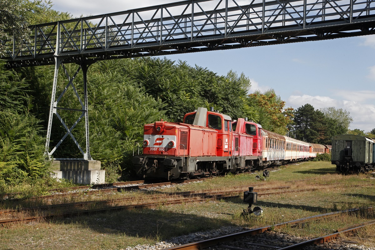 Unter dem Fußgehersteig stehen die 2067.090 und 2067.096 mit einigen Reisezugwagen.Das Bild stammt vom 21.09.2016. 