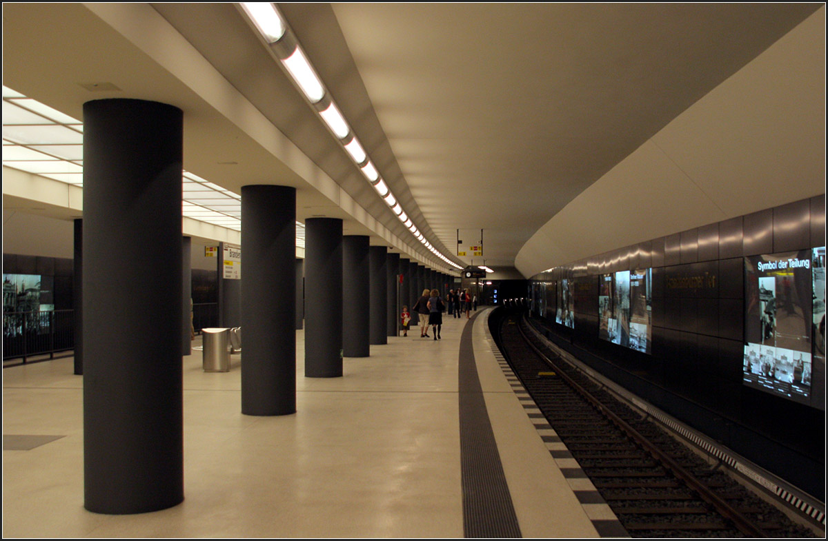 Unter dem Pariser Platz -

Blick auf eines der beiden Gleise der Station Brandenburger Tor. Die bergmännsiche Bauweise ist nicht so ohne weiteres zu erkennen. Anstelle von drei Röhren mit Durchbrüchen wurden die Röhren überschneidend gebaut mit Stützen an den Schnittpunkten. die Abschrägungen oberhalb der Stützen und oben an der Bahnsteigwand sind ein Hinweis auf die Röhrenform.

16.08.2010 (M)