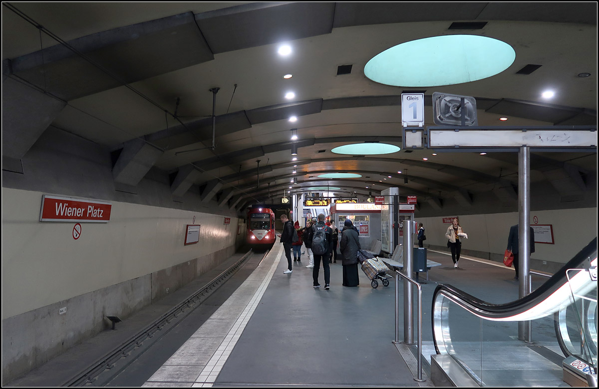 Unter dem Wiener Platz in Köln-Mülheim -

Seit 1997 fahren die Stadtbahnen die von der Mülheimer Brücke kommen unterirdisch durch Köln-Mülheim mit Halt am Wiener Platz und am Bahnhof Mülheim.

In meinen Augen hat die unterirdische Station am Wiener Platz ein besonderes Flair. Sie erinnert mich irgendwie an historische U-Bahnhöfe, vielleicht bedingt durch den flachen Bogen der Decke und dem Kiosk auf dem Bahnsteig. Durch die Oberlichter wird zudem die relativ geringe Tiefenlage erlebbar gemacht.

Wie auch den U-Bahnhof Severinstraße der Nord-Süd-Stadtbahn wurde auch diese Station von Kister Scheithauer Gross Architekten gestaltet.

16.10.2019 (M)
