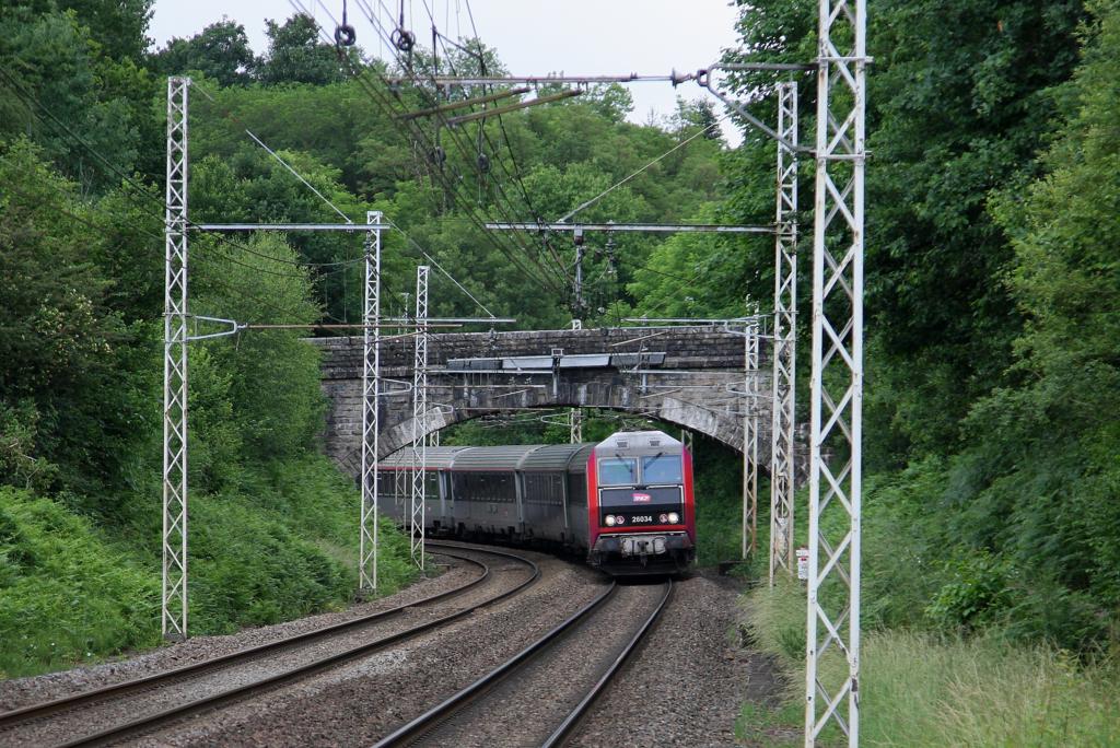 Unweit des kleinen Landbahnhof Magnac Vicq unterquert am 14.06.2015 die Sybic SNCF 26034 mit einem Schnellzug in Richtung Limoges um 15.45 Uhr eine steinerne Bogenbrücke. 
