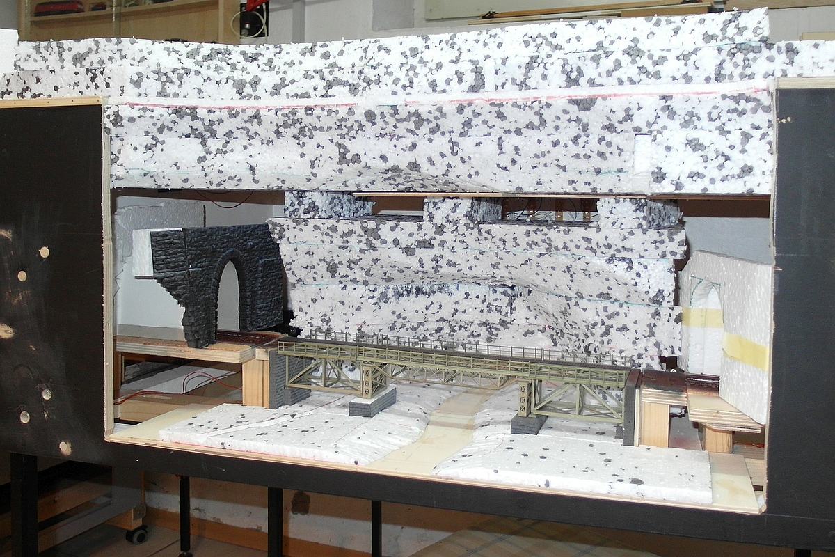 Update zu unserer im Bau befindlichen, aus sechs Modulen bestehenden Märklin H0-Anlage - Damit das Gleis in den Schattenbahnhof nicht nur unsichtbar unter den Moduloberflächen verläuft, haben wir an einem Modul eine Seite geöffnet und führen das Gleis durch einen kleinen Landschaftsausschnitt. Im Bild die aufgeschnittene Seite des Moduls zwischen  Kurvenmodul  und dem Modul zur Kehrschleife mit Gleiswendel. Hier werden die Züge zum bzw. vom Schattenbahnhof unter einem Felsüberhang einen Fluß und einen Kanal überqueren (März 2023)