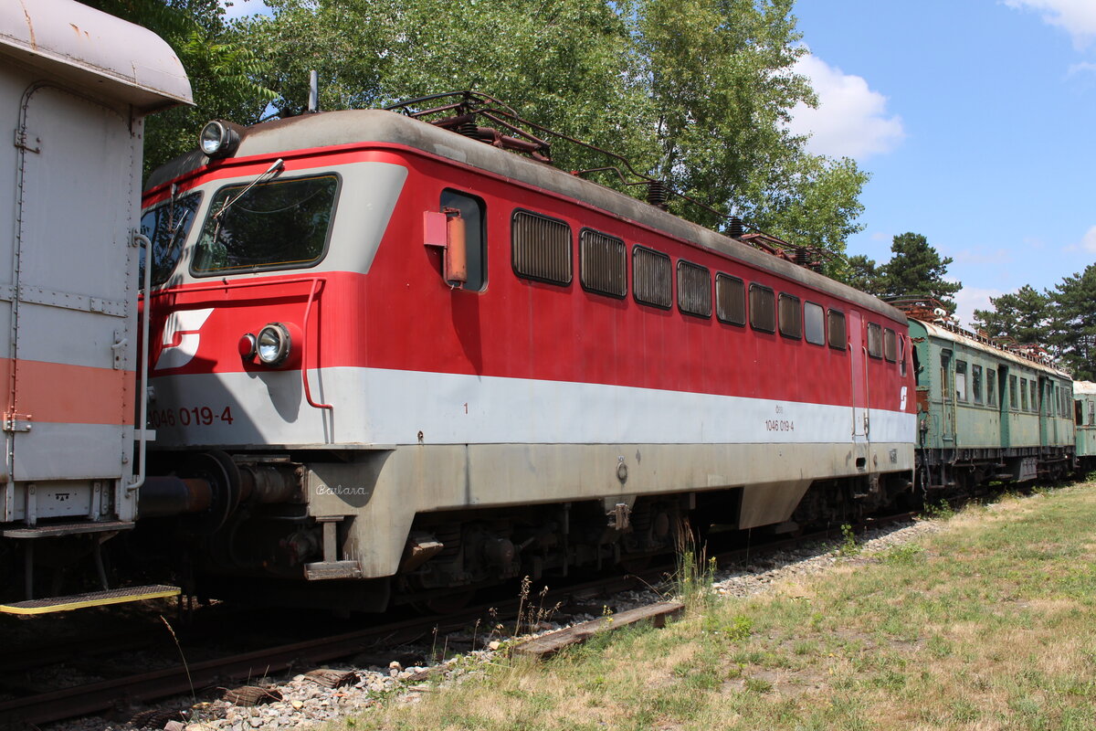 Ursprünglich in den 50er Jahren als Gepäcktriebwagen 4061 gebaut, wurde von 1987 bis 1994 die bereits als 1046 umnummerierte Lokreihe mit damals neueren Bauteilen und einem neuen Lokkasten aufgewertet.
Die eigentlich recht modern wirkende 1046 019  Barbara  steht nach ihrem letzten Einsatzgebiet bei ÖBB Nostalgie seit 2009 im Eisenbahnmuseum Strasshof wo sie am 12.7.2021 in der Sonne dahinbrutzelt.