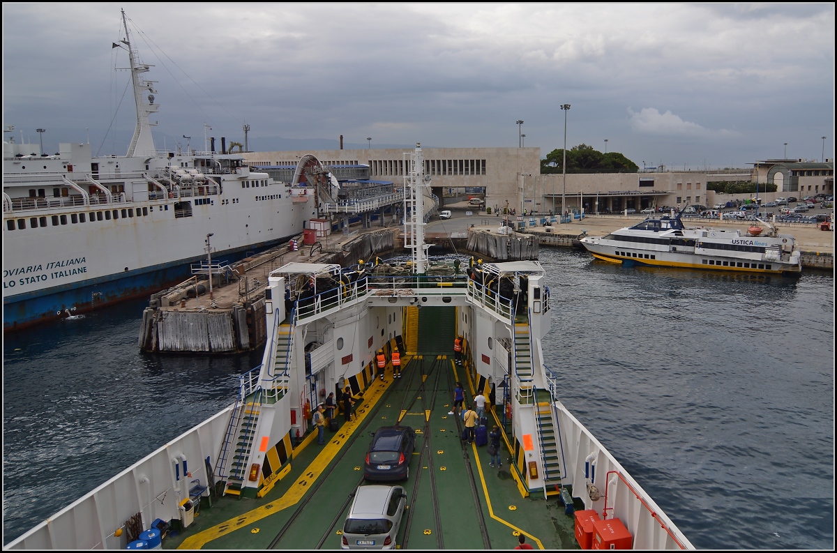 <U>Zwischen Skylla und Charybdis.</U>

Das Fährschiff der FS erreicht den Fährhafen und Bahnhof von Messina. Die Bahnsteige sind rechterhand der Bäume versteckt, linkerhand die Gleise um auf die Schiffe zu rangieren. Während die Fata Morgana, der Fotostandpunkt, unermüdlich die Personen und Fahrzeuge zwischen dem Festland und Sizilien herschüttelt, scheint das Schiff auf einen Zug zu warten. Messina im August 2013. 