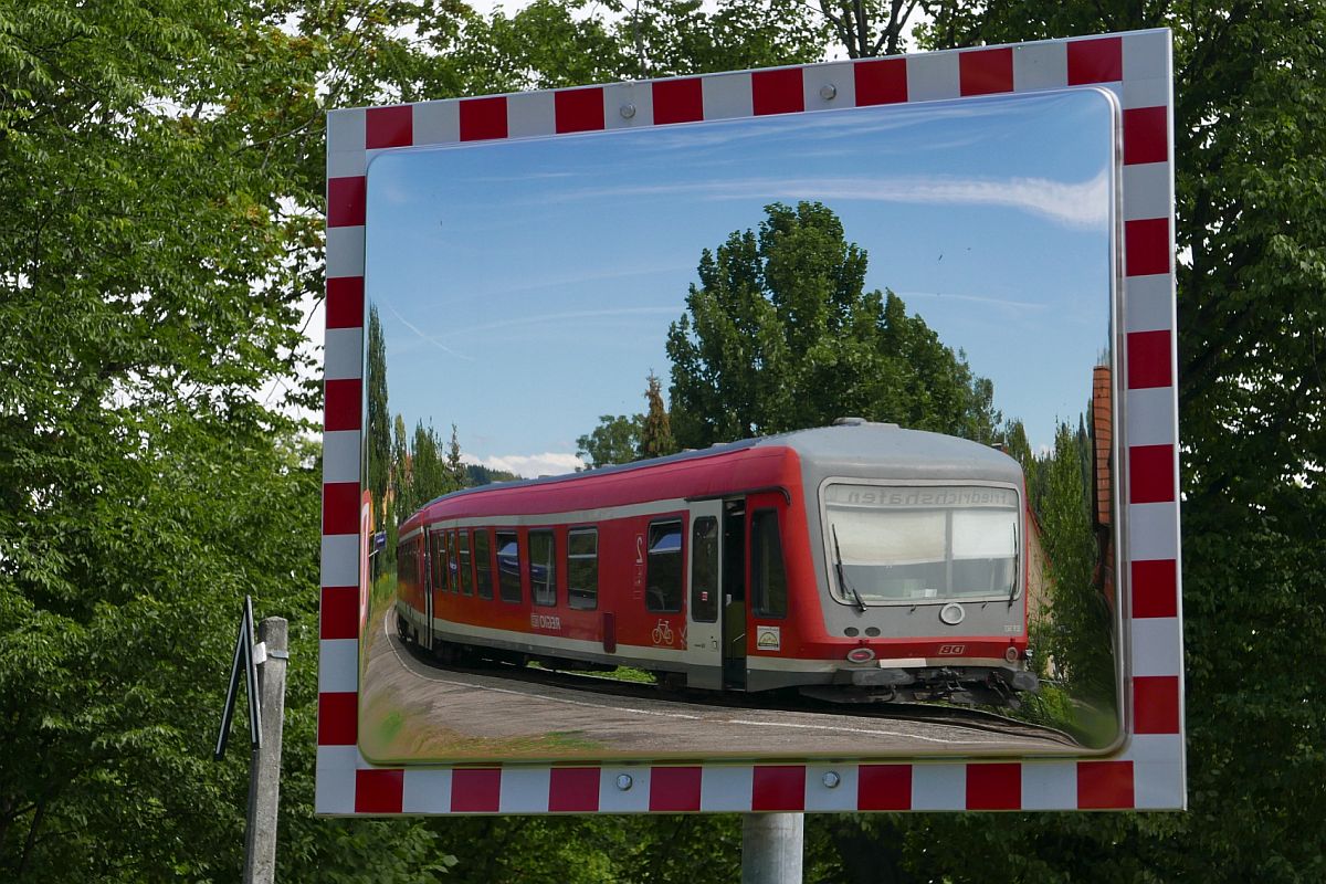 Verzerrt - 928/628 563 ist am 11.08.2018 als RB 22718 von Lindau nach Friedrichshafen-Hafen in die Haltestelle Lindau-Aeschach eingefahren und wurde in einem von zwei dort stehenden Spiegeln fotografiert.