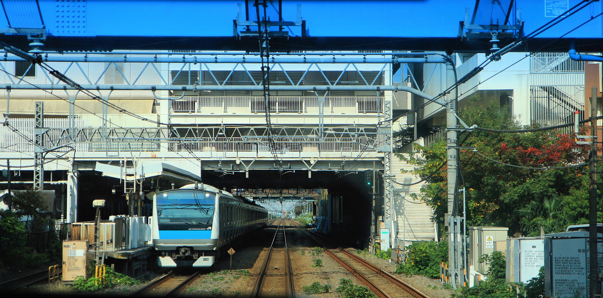 Viele Strecken im Umkreis der grossen Städte haben doppelte Doppelspur. Blick durch die verglaste Rückwand eines Eilzugs, der seine eigene Fahrbahn hat und an der Station Ôimachi vorbeibraust. Daneben wartet ein Zug mit Halt an allen Stationen (Zug 233-1008). 10.November 2018.  TÔKAIDÔ-LINIE 