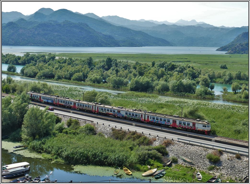 Vom Friedhof der Kirche Vranjina bietet sich ein wunderbarer Blick über den oberen Teil des Skutariesees/Skadarsko Jezero und die Bahnstrecke Podgorica - Bar. R6157 mit Riga-Triebzug 412-045 ist auf dem Weg nach Bar. (21.07.2019)
