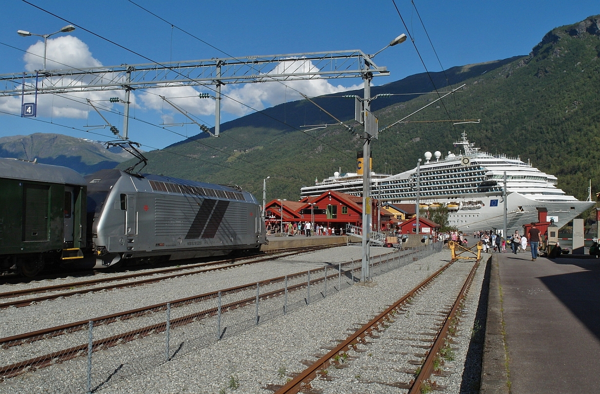 Vom Kreuzfahrtschiff auf kürzestem Weg in den Zug - El 18 2255 erreicht am 20.08.2015 mit dem Zug von Myrdal den Ziel- und Endbahnhof Flåm. Im Hintergrund liegt die Costa Fortuna, von dem aus Gäste bei Bedarf in wenigen Gehminuten in den Zug einsteigen und einen Ausflug mit der Flåmsbahn unternehmen können.