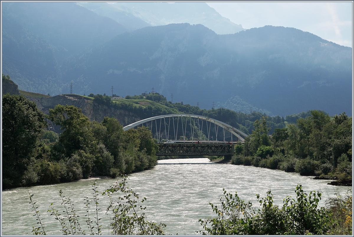 Vom Ufer der Rohne aus, auf der Walliser Seite, ein Blick auf die neue Rhonebrücke zwischen Bex und St-Maurice und die zum teil noch vorhandene alte Gittereisen Brücke.  
Zu Zeit ist die alte Brücke schon nicht mehr in Betrieb und der Verkehr verläuft einspurig über die neue Brücke, wobei vor und nach der Brücke das nördliche Gleis, dann auf der Brücke das Südliche Gleis benutzt wird, so dass die Brücke noch verschoben werden muss. Leider ist es nicht einfach, einen einigermasen guten Fotostandpunkt zu finden. Im Bild, gerade noch zu erkennen, ein SBB ETR auf der Fahrt von Milano nach Genève.
19. August 2016