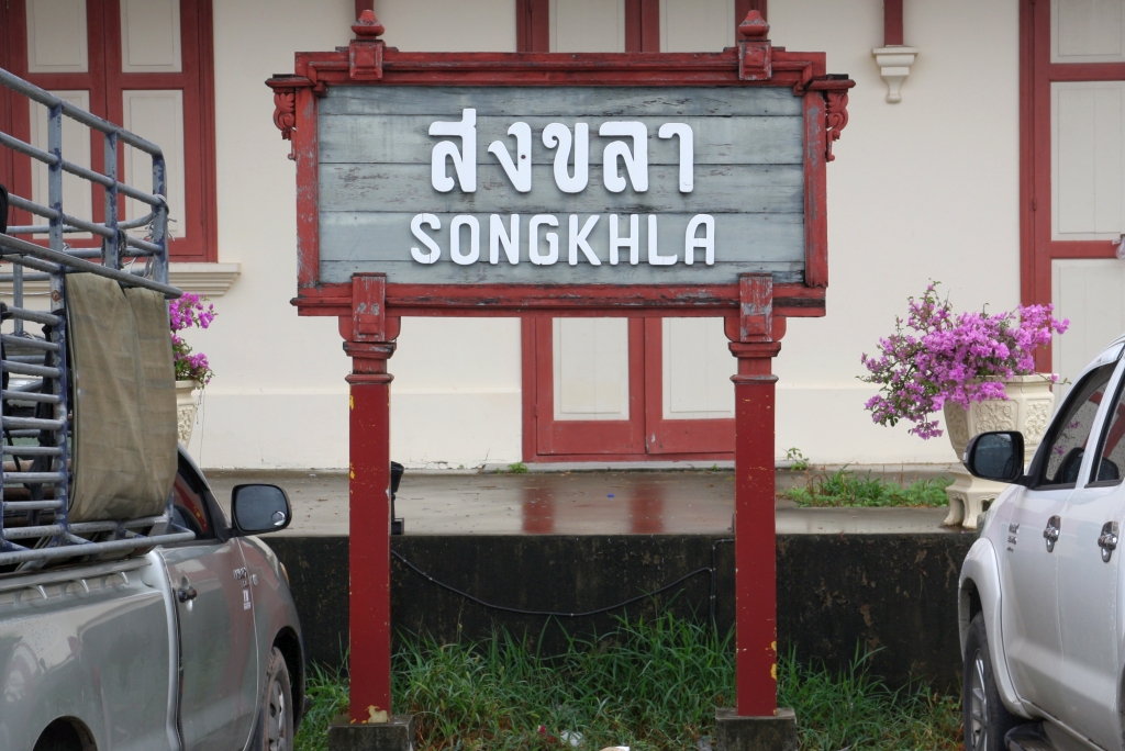 Von der 1978 eingestellten Bahnlinie Hat Yai - Songkhla ist das seit 2004 unter Denkmalschutz stehende Aufnahmsgebäude der Songkhla Station noch erhalten. Stationsschild am Vorplatz, Bild vom 07.Jänner 2023.