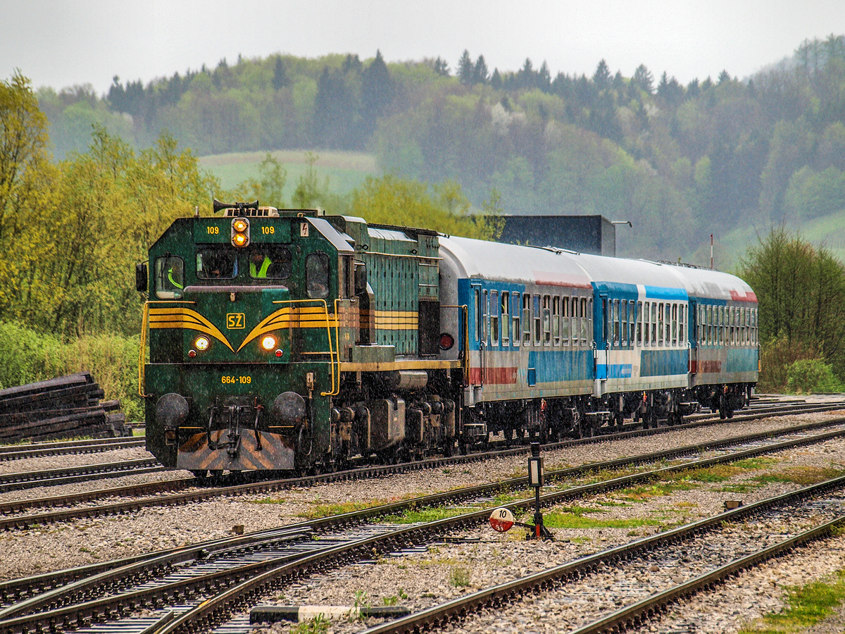 Von Dieselloks bespannte Personenzüge sind in Slowenien eine Seltenheit und sind in der Regel nur beim Schnellzugpaar 246/7 von Ljubljana nach Budapest anzutreffen, oder zufälligerweise, wenn ein Triebwagen wegen eines Defekts ausfällt. Dementsprechend sehenswert war der durch britische Eisenbahnfreunde gemietete Sonderzug. Die geplante Route für den 18.04.2015. war Ljubljana – Zidani Most – Celje – Rogatec – Djurmanec (HR) – Zabok – Zapresic – Dobova (SLO) – Sevnica – Trebnje – Grosuplje – Ljubljana. Bei strömenden Regen fährt die 664 109 mit drei slowenischen Abteilwagen am Haken in den Grenzbahnhof Rogatec ein, wo eine Passkontrolle sowie der Lokwechsel auf die kroatische 2062 024 erfolgen werden.