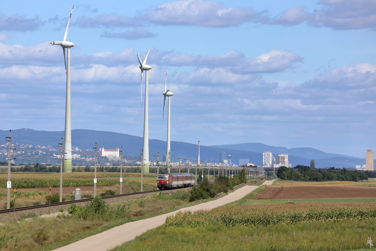 Von einem Hochstand in Pama aus entstand diese Aufnahme des IC 44 auf der Fahrt von Bratislava nach Wien. Die mächtigen Windräder neben der Bahnstrecke lassen die 383.107 mit ihrem Zug winzig erscheinen. (27.08.2020)