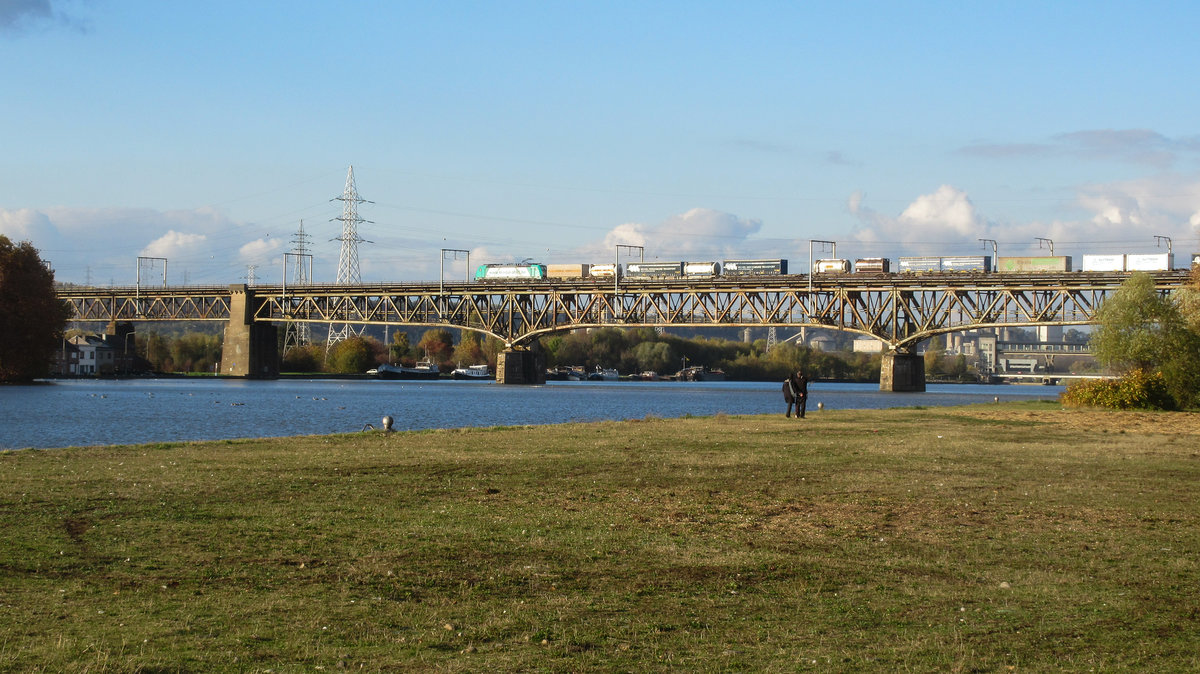 Von einem Spaziergängerpaar beobachtet überquert Cobra-Lok 2825 mit ihrem gemischten Güterzug die Maasbrücke in Visé gen Tongeren. Aufnahme vom 05/11/2016.