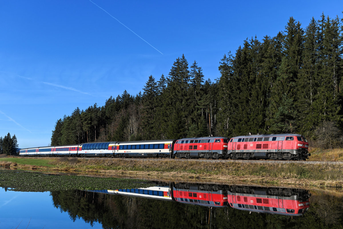 Von Eisenbahnfotografen stets gut besucht war der Ruderatshofener Weiher. Am 14. November 2020 spiegelten sich dort die 218 433 und 403 in der ruhigen Wasseroberfläche, als sie mit ihrem EC 191 nach München HBF vorbeifuhren. An den Abgashutzen kann man erkennen, das beide Loks jeweils mit einem Motor des Typs MTU 4000 ausgerüstet sind. 
