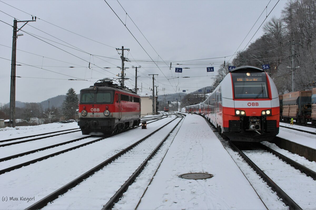 Von der slowenischen Seite des Bahnhofs Spielfeld-Straß rollt am 23.1.2023 die 1142 667 durch den Bahnhof um im österreichischen Teil wieder mit eigener Kraft ihre nächste Leistung zu tätigen.
Rechts wartet der 4744 038 als D156 auf die Abfahrt nach Graz Hbf.