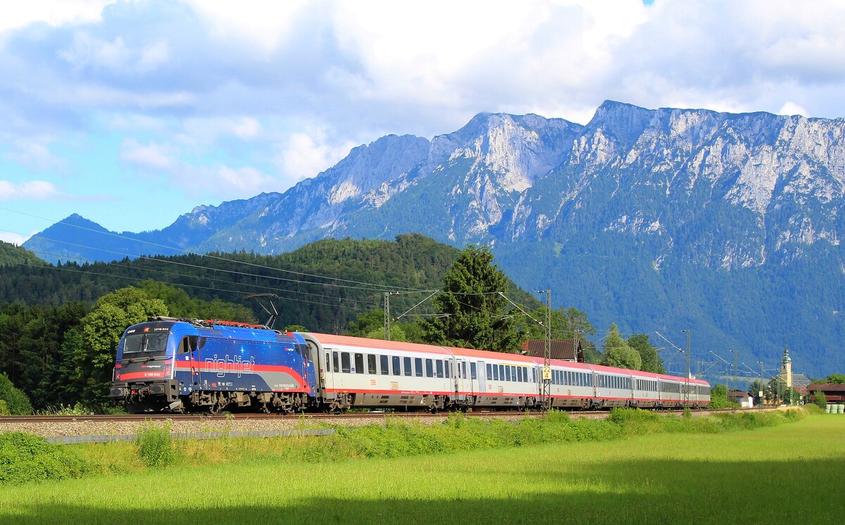 Vor Alpenpanorama präsentiert sich ein Eurocity mit populärer Taurus 1116 195  Nightjet  am 11.07.2021 bei Oberaudorf.