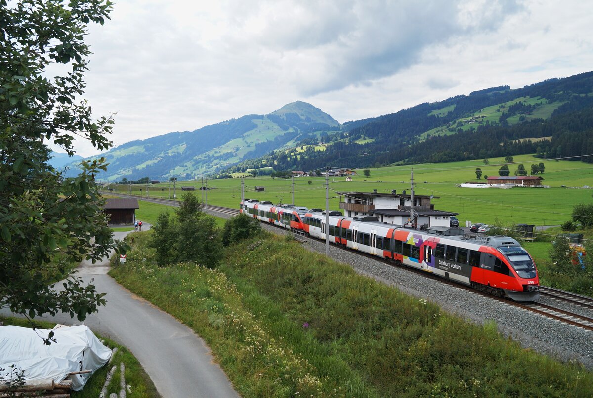 Vor dem Panorama der Hohen Salve schlängelt sich der REX 1521 (Wörgl Hbf - Schwarzach-St. Veit) bei Kirchberg Bockern um die Kurve. Die Aufnahme stammt vom wolkenverhangenen 25. Juli 2020, an dem die Leistung von den beiden Salzburgern 4023 001 und 4023 002 geführt wurde. Dabei handelt es sich um die ältesten Triebzüge der ÖBB-Talent-Triebwagen, die zum Zeitpunkt der Aufnahme 16 Jahre alt waren.