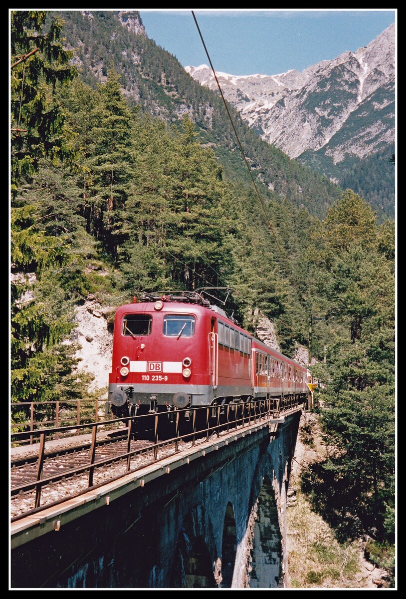 Vor der Gebirgskulisse des Karwendelgebirges fährt 110 235 am 16.05.2000 mit R5422 über den Kaiserstandviadukt.