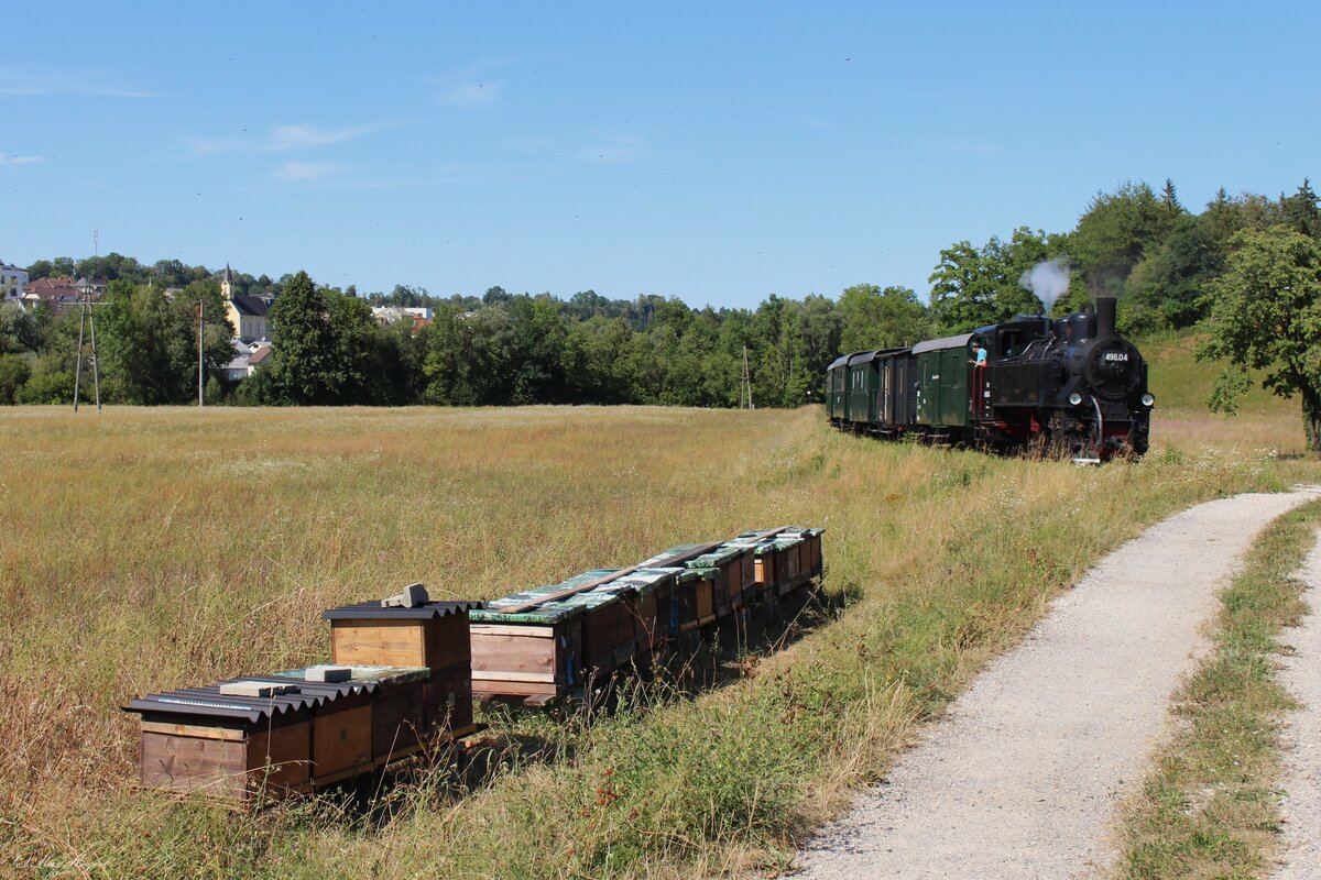 Vor der Haltestelle Neuzeug rollt die 498.04 am 25.7.2026 mit einem kurzen Personenzug in Richtung Gr�nburg.
Im Hintergrund ist die r�misch-katholische Filialkirche Maria Lourdes in Sierninghofen zu sehen.