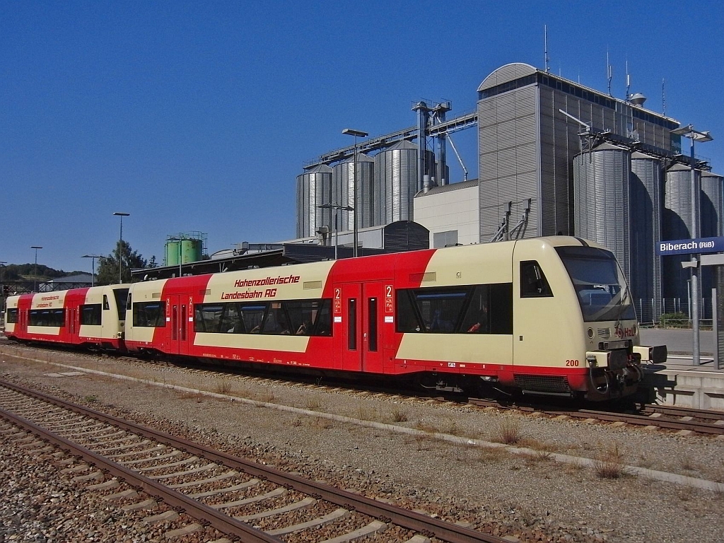 Vor den im Hintergrund stehenden Getreidesilos der BayWa fahren am 02.08.2013 VT 212 und VT 200 der Hohenzollerischen Landesbahn im Bahnhof von Biberach (Ri) ab. Die beiden Triebwagen befinden sich als RB 22618 auf der Fahrt von Sigmaringen nach Ulm.