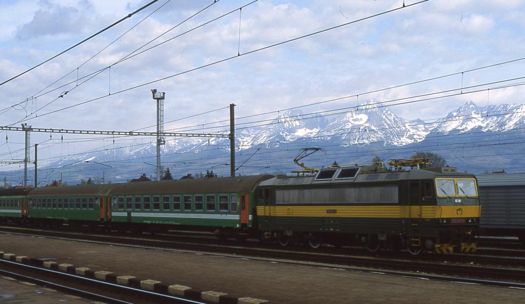 Vor der imposanten Bergkulisse der hohen Tatra fhrt am 2.5.2003 Elektrolok
162007 mit einem OS aus Richtung Strba in den Bahnhof Poprad Tatry ein.