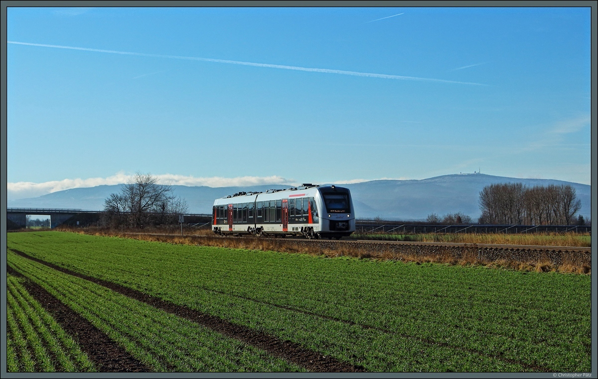 Vor der Kulisse des schneebedeckten Brockengipfels eilt der Abellio-Triebwagen 1 648 439 bei Heudeber als RE 75757 dem nächsten Halt in Halberstadt entgegen. (19.01.2022)