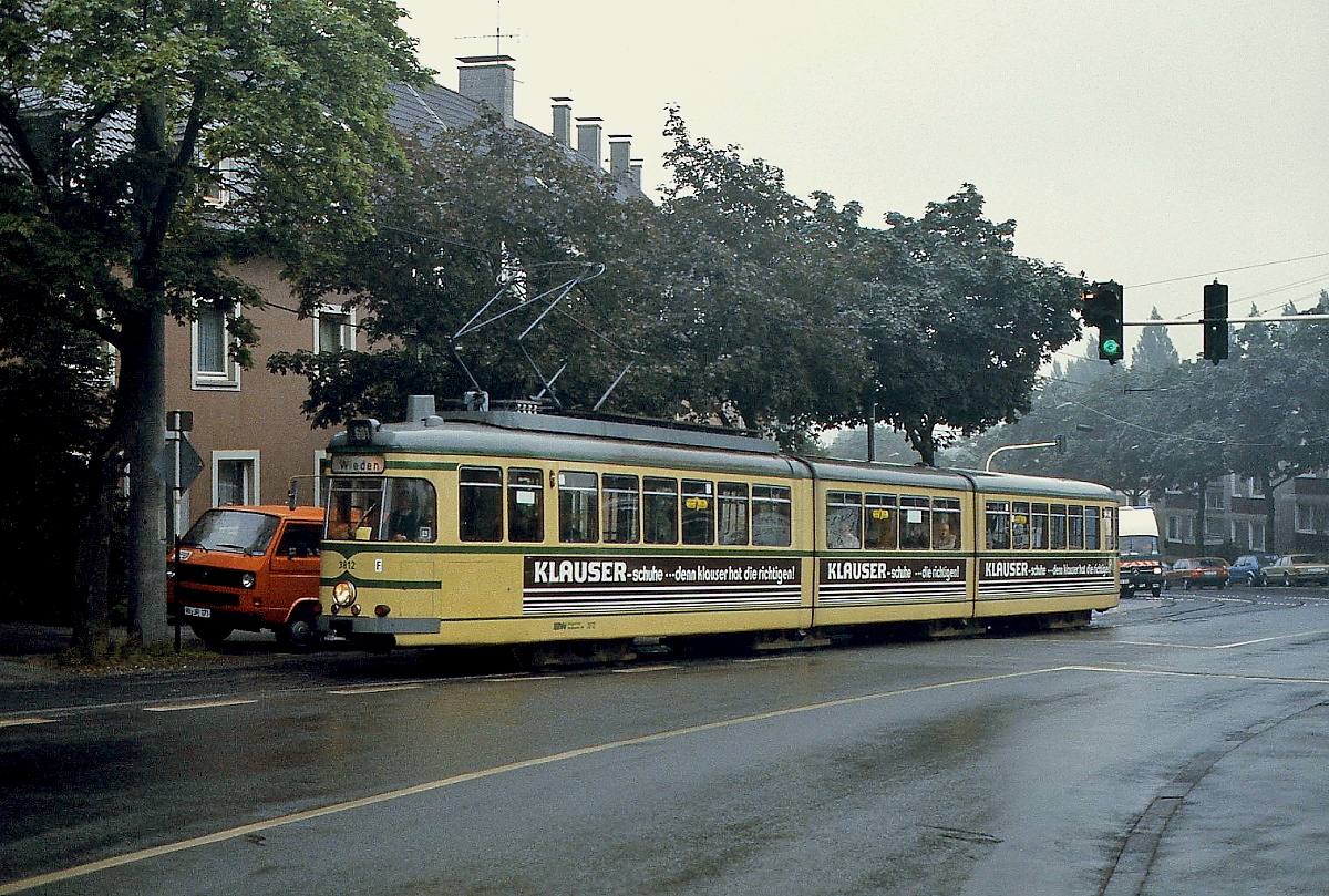 Vor mehr als 30 Jahren, am 30.05.1987, wurden die letzten beiden Linien der Wuppertaler Straßenbahn eingestellt. Zuletzt verkehrten nur noch Bahnen von Heckinghausen zum Gabelpunkt und nach Wieden. Mitte der 1980er Jahre entstand diese Aufnahme des Tw 3812 in der klassischen Wuppertaler Lackierung auf der Fahrt nach Wieden. Der Triebwagen gehört zur Serie 3801-3816 (bis 1979 8001-9016), die durch den Umbau von Vierachsern der Serie 1005-1020 entstand.