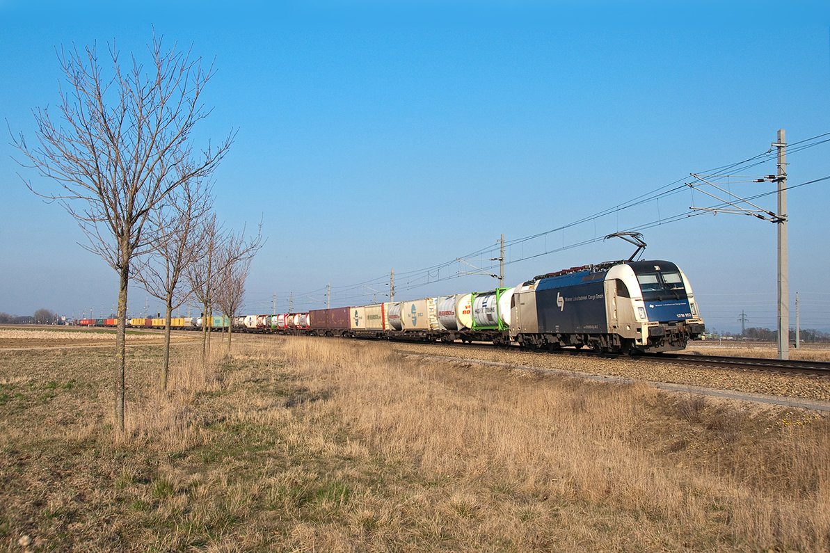 Vor den noch kahlen Bäumchen in Tullnerfeld fährt die WLC 1216 953 mit ihrem Güterzug in Fahrtrichtung St. Pölten. Die Aufnahme entstand am 20.03.2015.