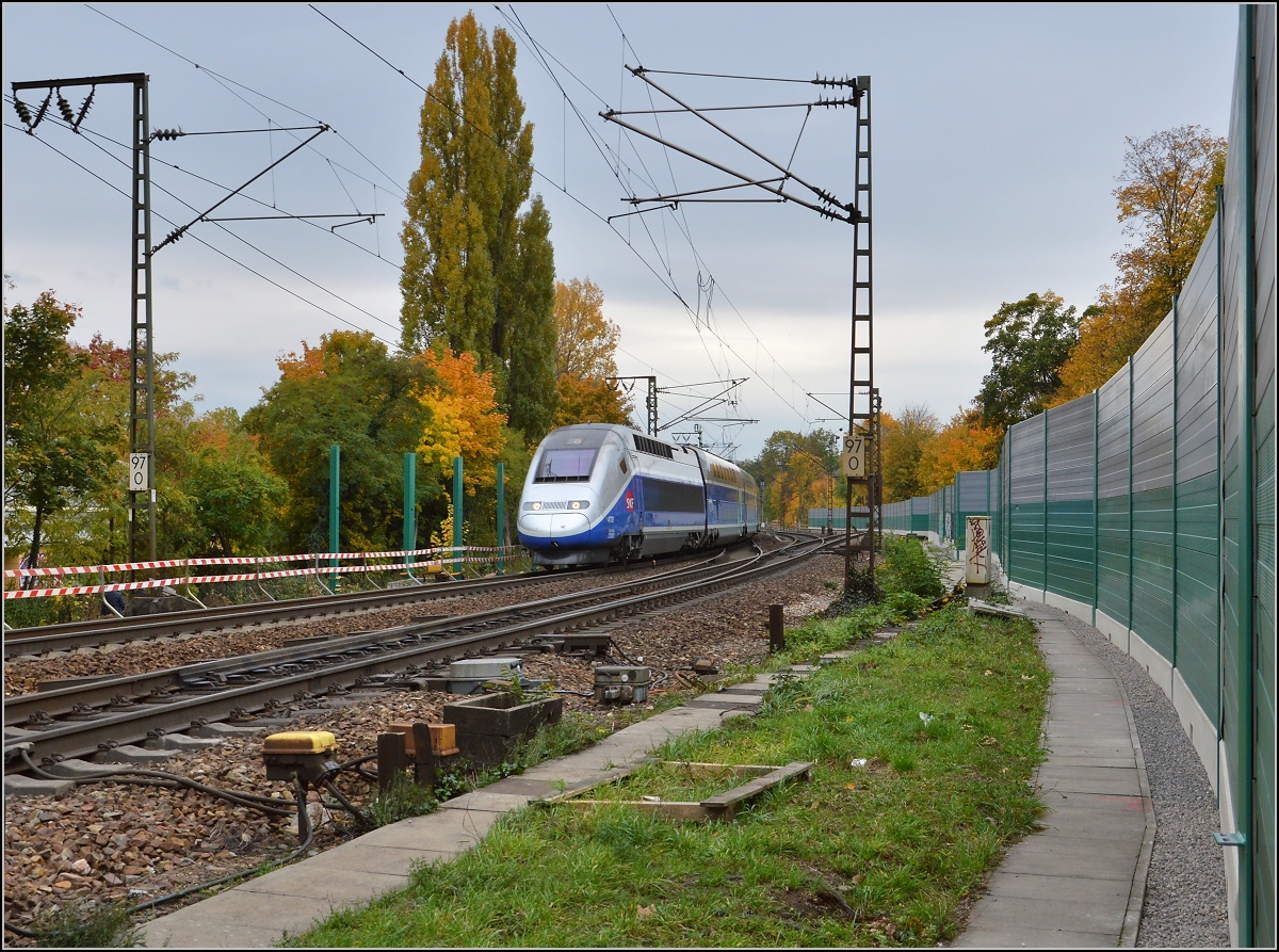Vorbei ist's mit der Fotoherrlichkeit am Rastatter Nadelöhr. 

Der Straßenbahn entgegen kommt der TGV nach München. Oktober 2015.

Für Zweifler: Erstaunlicherweise konnte man noch erlaubt durch eine Lücke in der neuerrichteten Schallschutzwand lugen ohne den Gleisbereich zu betreten.
