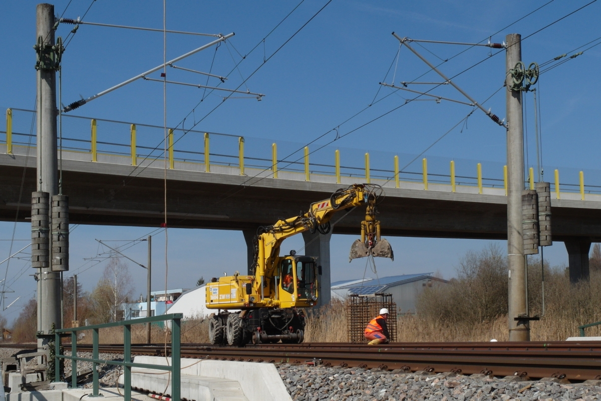 Vorher# Oberleitungsmasten aus Beton. Am 28.03.2015 stehen zwischen den Haltestellen Reichenau und Wollmatingen zwei Masten aus Beton, w�hrend ein Zweiwegebagger (ATLAS 1604ZW) von Balfour Beauty die Fundamentarbeiten f�r neue Stahlmasten unterst�tzt, die die Betonmasten ersetzen werden.