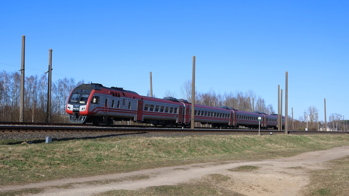 Vorortzug 837 Sigulda - Riga der AS Pasažieru Vilciens kurz nach der Überfahrt über den Fluss Jugla. Diese Leistung wurde von einer der drei modernisierten Garnituren vom Typ DR1AC erbracht. Im Gegensatz zum sowjetlettischen Fahrzeugmaterial vom Typ DR1A verfügt dieser unter anderem über eine Klimaanlage.
Aufgenommen im April 2026.