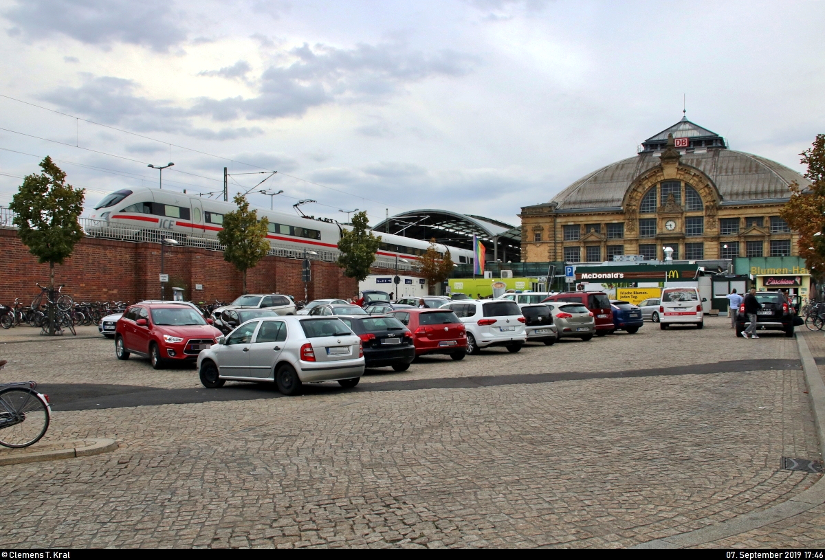 Vorplatzansicht von Halle(Saale)Hbf mit Empfangsgebäude, parkenden Autos und abfahrendem 411 571-3 (Tz 1171  Oschatz ) als ICE 1631 (Linie 15) von Frankfurt(Main)Hbf nach Berlin Gesundbrunnen.
Seit dem 31.3.2017 ist der Platz nach dem in Halle-Reideburg geborenen ehemaligen Politiker Hans Dietrich Genscher benannt.
[7.9.2019 | 17:46 Uhr]