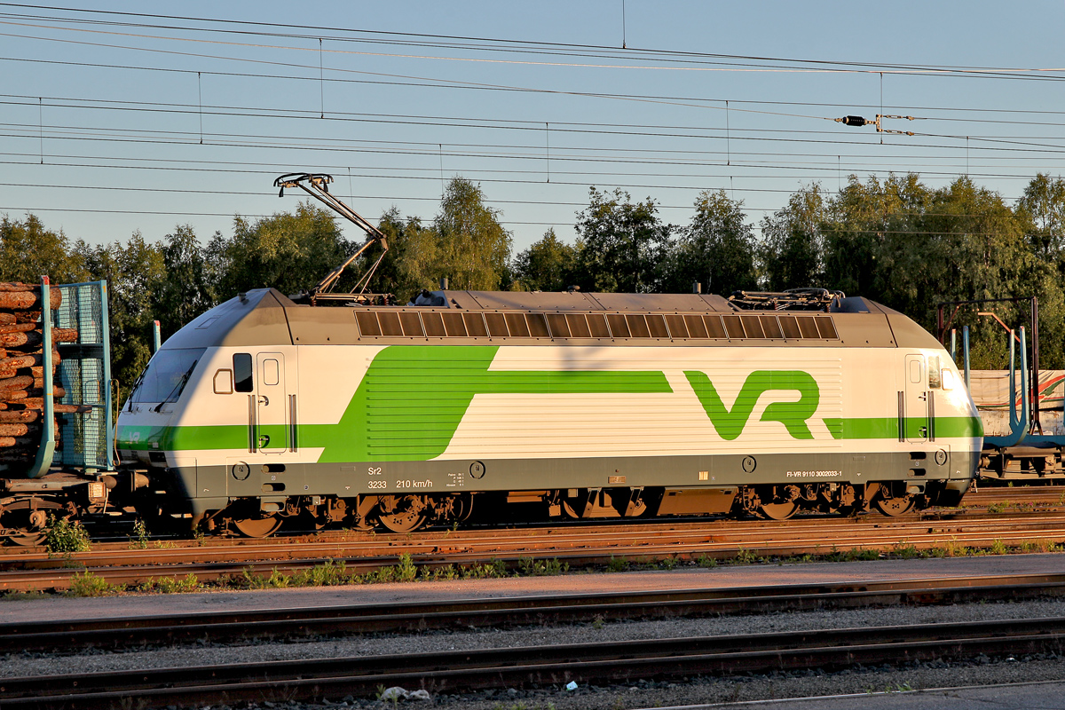Vr Lok Sr 2 3233 steht angespannt fahrbereit vor einem Holzzug und sonnt sich noch unter der Mitternachtssonne bevor es nach Süden geht.Bild vom 7.7.2014