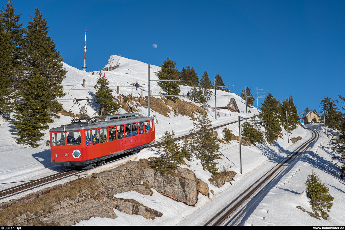 VRB Bhe 2/4 2 von 1937 am 16. Februar 2019 auf Talfahrt zwischen Rigi Kulm und Rigi Staffel. Auf der parallelen ARB-Strecke verschwindet gerade der BDhe 2/4 12 auf Bergfahrt hinter der Kurve.