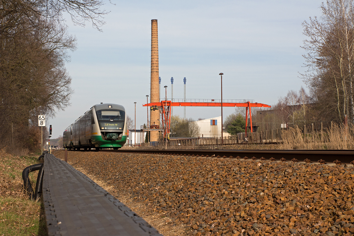 VT 07 A der Trilex verließ am frühen Abend des Ostersonntages 2016 den Bahnhof Bischofswerda und strebte als  TLX2  sein Fahrtziel Dresden Hbf an.

Rechts im Bild erkennt man einen von zwei Takraf-Brückenkranen des ehemaligen Mähdrescherwerkes  VEB Fortschritt Bischofswerda . (27.03.16)