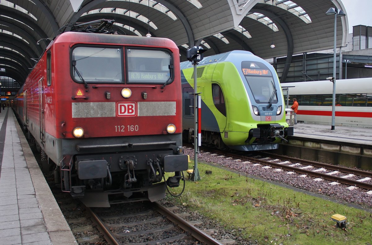 Während 112 160 mit dem RE70 (RE21023) nach Hamburg Hauptbahnhof im Kieler Hauptbahnhof auf Abfahrt wartet, macht sich 445 013-9 als RE7 (RE21123) nach Hamburg Hauptbahnhof auf den Weg.