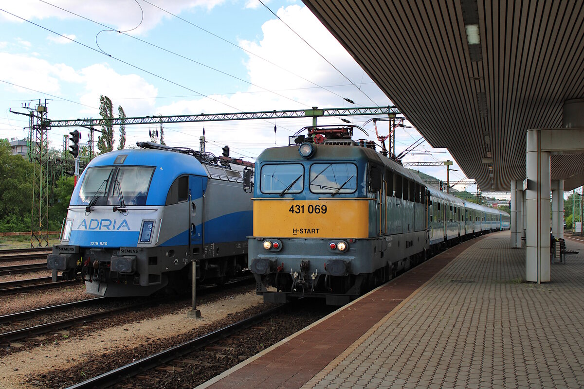 Während 431 069 der MAV mit IC 826  Somogy  (Budapest-Keleti - Gyékényes) in Budapest-Kelenföld einfährt steht im Nachbargleis Adria 1216 920 abgestellt und wartet auf ihren nächsten Einsatz. (09.05.2023)