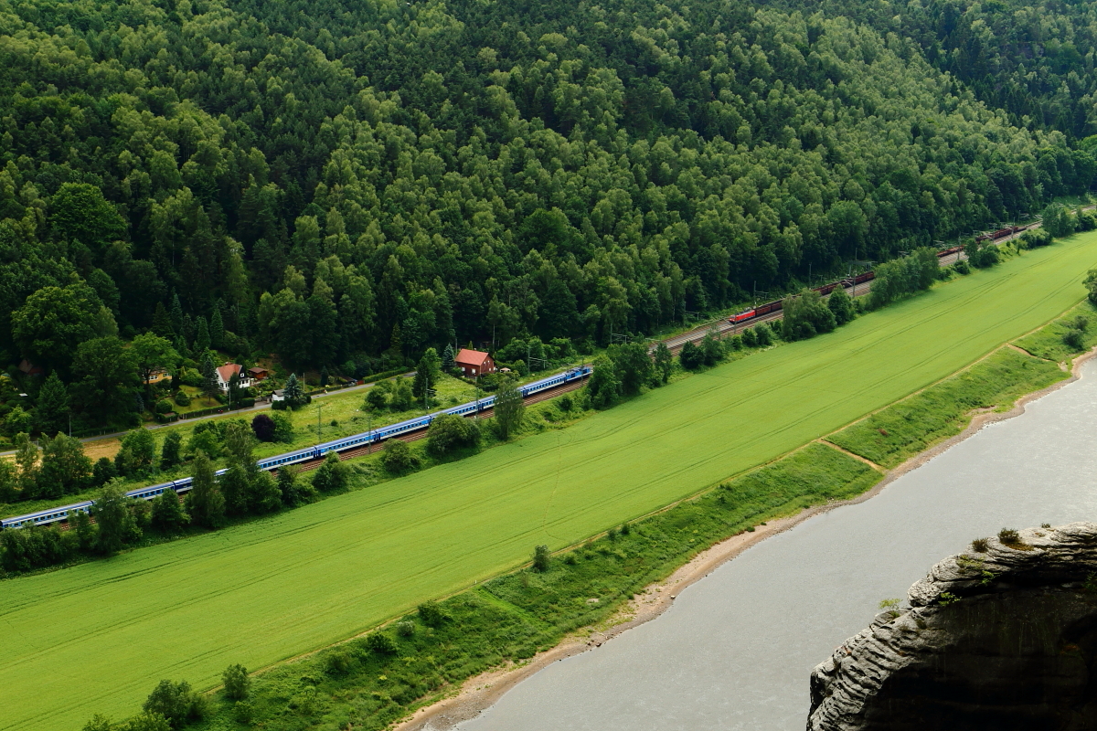 Während am 16.06.2017 ein EC, aus Tschechien kommend, in Richtung Dresden unterwegs ist, kommt ihm, laut dröhnend, ein gemischter Güterzug entgegen. Die Aufnahme entstand vom Bastei-Felsen aus.